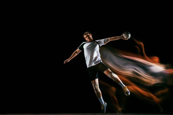 Young handball player against dark studio background in mixed light - Fotoğraf, Görsel