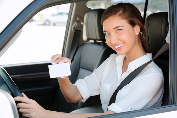 girl in a car showing an empty white card for your message - Fotó, kép