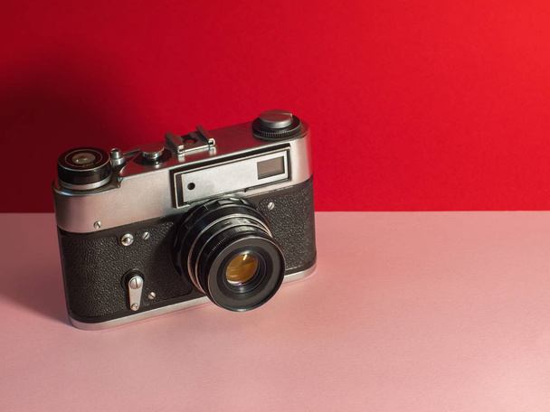 Old film camera on a Living Coral Trend vintage, travel top view copy space - 写真・画像