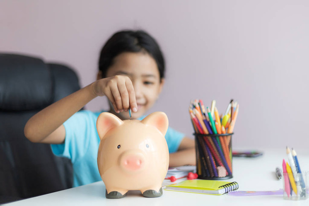 Szczęśliwy trochę Asian Dziewczyna oddanie pieniądze moneta w Piggy Bank Selec - Zdjęcie, obraz