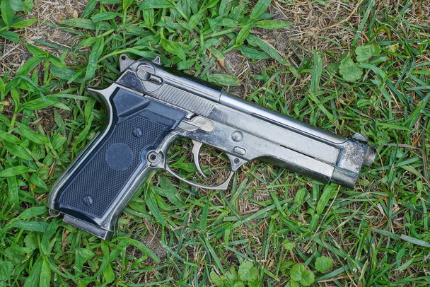 un pistolet gris se trouve sur l'herbe verte dans la rue
 - Photo, image