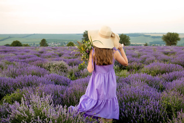 Woman in purple dress and hat in lavender field. - Foto, immagini
