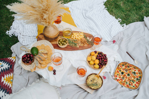 Appetizers table for picnic, full of snack. White cloth spread over lawn - Foto, afbeelding