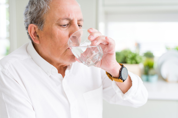 Bonito senhor sênior bebendo um copo de água fresca em casa
 - Foto, Imagem
