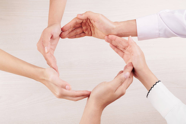 Gruppe von Menschen bilden Kreis aus Händen zusammen und demonstrieren ihre Freundschaft und Einheit vor weißem Hintergrund - Foto, Bild