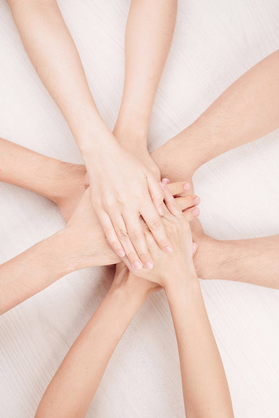Close-up of Caucasian people holding hands together against the white background - Valokuva, kuva