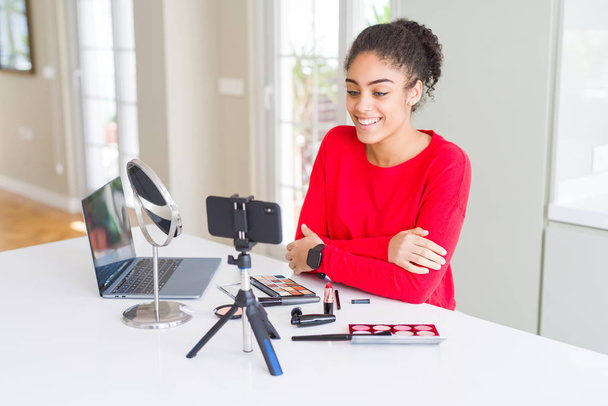 Jonge African American influencer vrouw opname make-up tutorial met een gelukkige en koele glimlach op het gezicht. Gelukkige persoon. - Foto, afbeelding