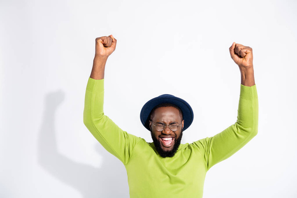 Portrait of ecstatic man with closed eyes screaming shouting yeah wearing green sweater isolated over white background - Photo, Image
