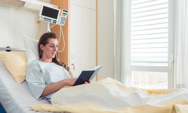 Γυναίκα στο κρεβάτι του νοσοκομείου διαβάζοντας τη Βίβλο - Φωτογραφία, εικόνα