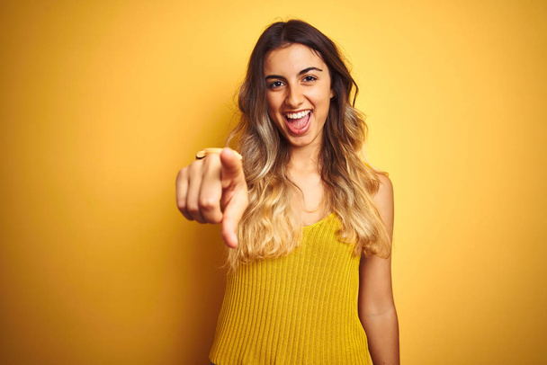 junge schöne Frau trägt T-Shirt über gelbem Hintergrund und zeigt unzufrieden und frustriert in die Kamera, wütend und wütend auf dich - Foto, Bild