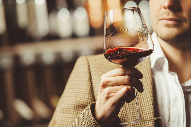Bokal of red wine on background, male sommelier appreciating drink - Fotoğraf, Görsel
