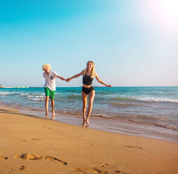 Happy young couple having fun at beach on sunny day - Photo, Image