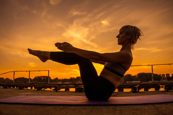 Woman exercising pilates in sunset. Teaser exercise.  - Foto, Bild