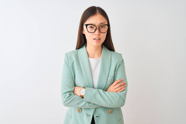 Chinese businesswoman wearing elegant jacket and glasses over isolated white background skeptic and nervous, disapproving expression on face with crossed arms. Negative person. - Photo, Image