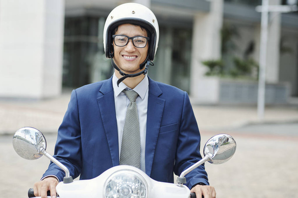 Ritratto di giovane uomo d'affari vietnamita in casco seduto su scooter e sorridente alla macchina fotografica
 - Foto, immagini