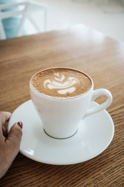 Female hand holds a cup of cappuccino - Φωτογραφία, εικόνα