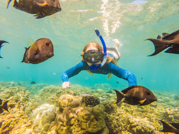 サンゴ礁の海のプールで熱帯魚と水中ダイビングシュノーケリングマスクの幸せな女性。旅行ライフスタイル、ウォータースポーツアウトドアアドベンチャー、夏のビーチホリデーでの水泳レッスン - 写真・画像