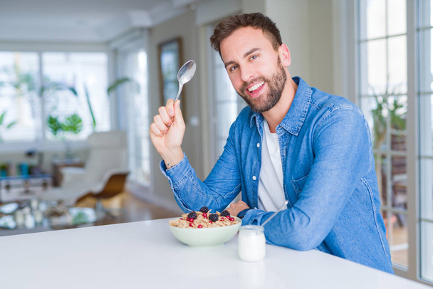 Komea mies syö aamiaista muroja kotona ja hymyilee
 - Valokuva, kuva