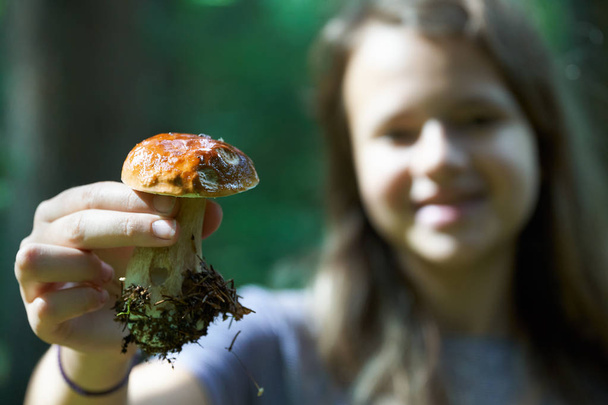 Teini tyttö osoittaa sieni boletus edulis kädessä metsässä
 - Valokuva, kuva