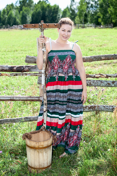 Pretty countrywoman with wooden rake and bucket - Valokuva, kuva