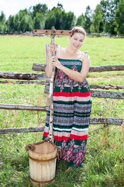 Pretty brunette with rake and bucket in a field - Valokuva, kuva