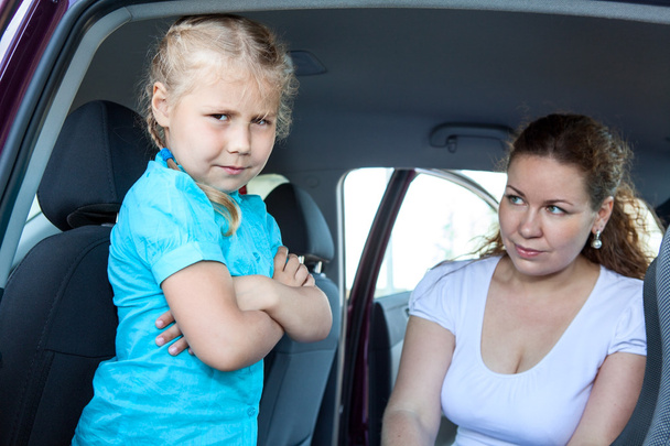 Caucasian girl does not want fastening in child safety seat in car - Foto, afbeelding