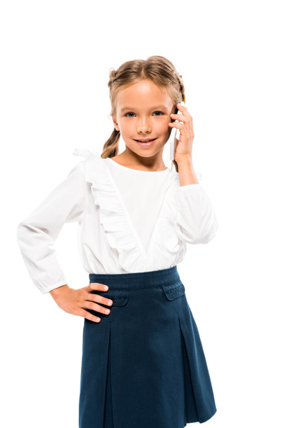 cute kid standing with hand on hip and talking on smartphone isolated on white  - Valokuva, kuva