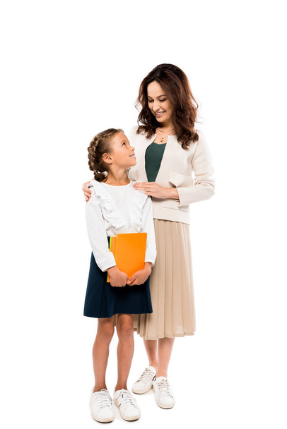 happy mother standing with cheerful daughter holding books isolated on white - Valokuva, kuva