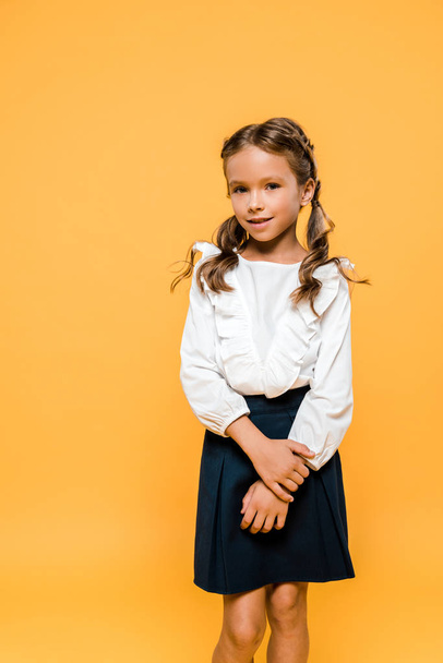happy schoolgirl smiling and standing isolated on orange  - Foto, Imagen