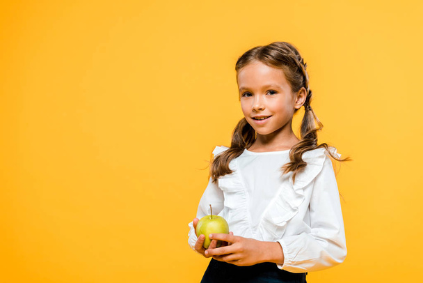 ευτυχισμένο παιδί που κρατά νόστιμο μήλο και χαμογελά απομονωμένα σε πορτοκαλί  - Φωτογραφία, εικόνα