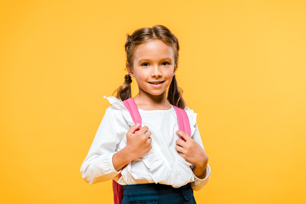 happy schoolkid touching pink backpack isolated on orange  - Фото, изображение