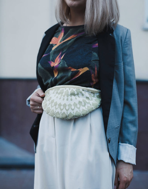 通りに立っているベージュのベルトコットンバッグを持つ若い美しい女性. - 写真・画像