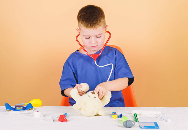 Boy cute child future doctor career. Health care. Kid little doctor busy sit table with medical tools. Medical examination. Medicine concept. Medical procedures for teddy bear. Medical education - Zdjęcie, obraz