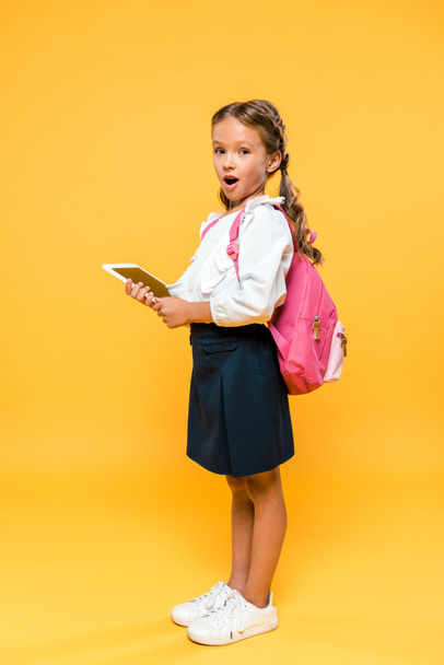 surprised schoolkid holding digital tablet with blank screen on orange  - Foto, Imagem