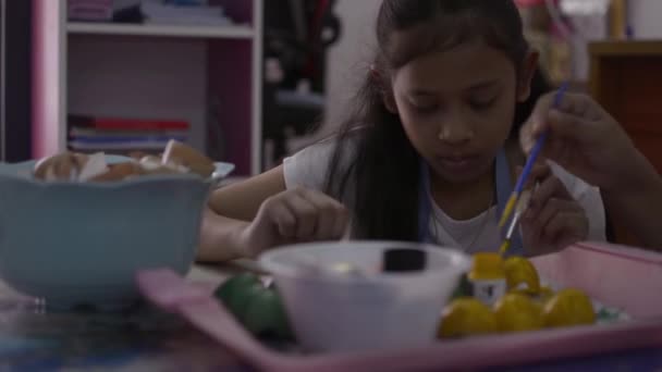 Asijská dívka a její matka dělají řemeslné výrobky z skořápek, matka pomáhá její dceři malovat skořápky společně doma, vzdělávací koncept. - Záběry, video