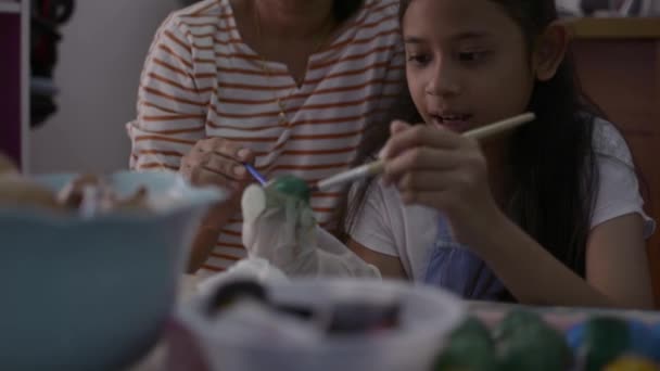 Asiática chica y su madre están haciendo artesanía de las cáscaras de huevo, Madre ayudando a su hija pintando cáscaras de huevo juntos en casa, concepto de educación
. - Metraje, vídeo