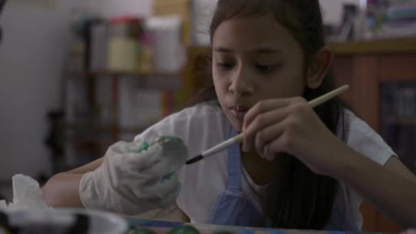 アジアのかわいい女の子は、机の上に卵の殻から工芸品を作っている、若い女の子は彼女の宿題、教育の概念のために自宅で卵の殻を着色しています. - 映像、動画