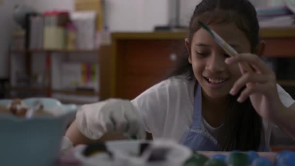 Asya sevimli kız masada yumurta kabukları el sanatları yapıyor, Genç kız ödevi için evde yumurta kabukları boyama, Eğitim kavramı. - Video, Çekim