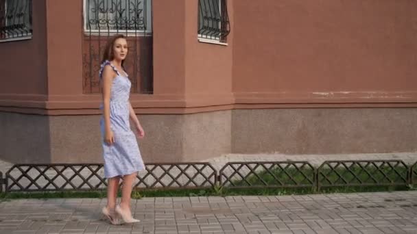 λεπτό Ευρωπαϊκό μοντέλο σε μοντέρνο μπλε φόρεμα περπατάει κατά μήκος του δρόμου - Πλάνα, βίντεο