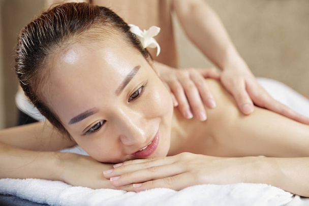 Uśmiechnięta Ładna Młoda Azjatycka kobieta korzystających z procedury masażu pleców w salonie Spa - Zdjęcie, obraz