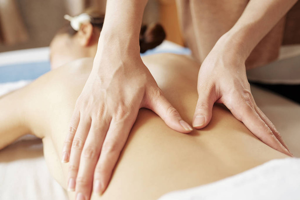 Mani di massaggiatore professionista massaggiando indietro di cliente femminile giovane
 - Foto, immagini