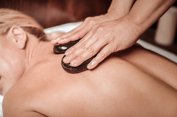 Massaggiatrice premendo pietre calde sul retro
. - Foto, immagini