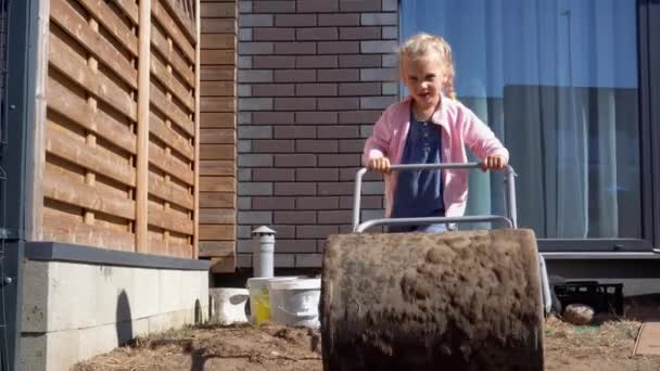 mother helper girl daughter leveling soil with huge roller in backyard - Footage, Video
