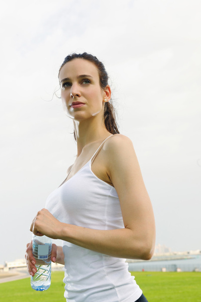 Young beautiful woman drinking water after fitness exercise - Foto, imagen