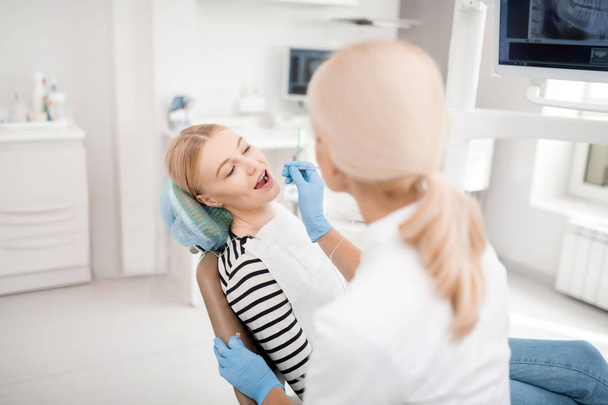 Calm patient opening her mouth during dental treatment. - Photo, Image
