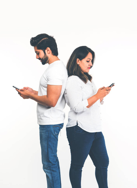 Indyjska para za pomocą smartfona/telefonu komórkowego, stojący na białym tle - Zdjęcie, obraz