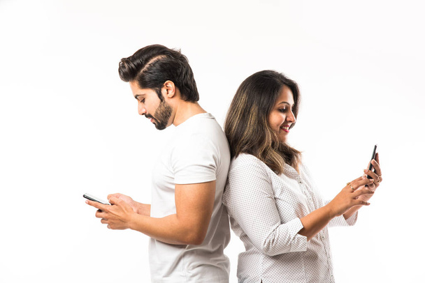 Ινδικό ζευγάρι χρησιμοποιώντας smartphone/κινητό ακουστικό, στέκεται απομονωμένη σε λευκό φόντο - Φωτογραφία, εικόνα