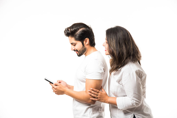 Coppia indiana utilizzando smartphone / cellulare, in piedi isolato su sfondo bianco
 - Foto, immagini