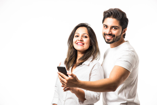 Indiai házaspár segítségével smartphone/mobil készülék, állandó izolált fehér háttér - Fotó, kép