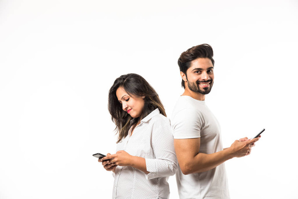 Ινδικό ζευγάρι χρησιμοποιώντας smartphone/κινητό ακουστικό, στέκεται απομονωμένη σε λευκό φόντο - Φωτογραφία, εικόνα